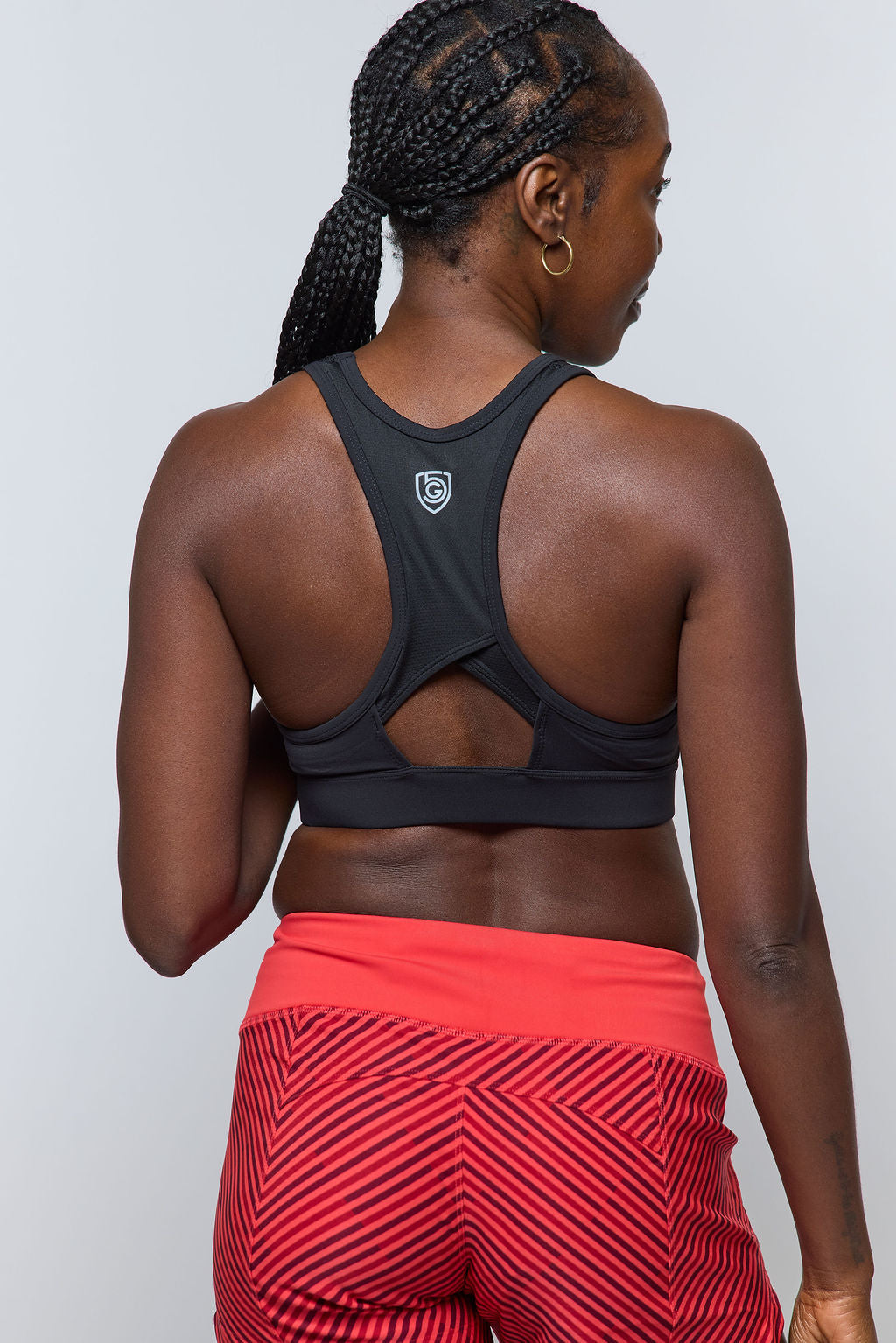Woman from behind wearing black sports bra and red patterned workout shorts.