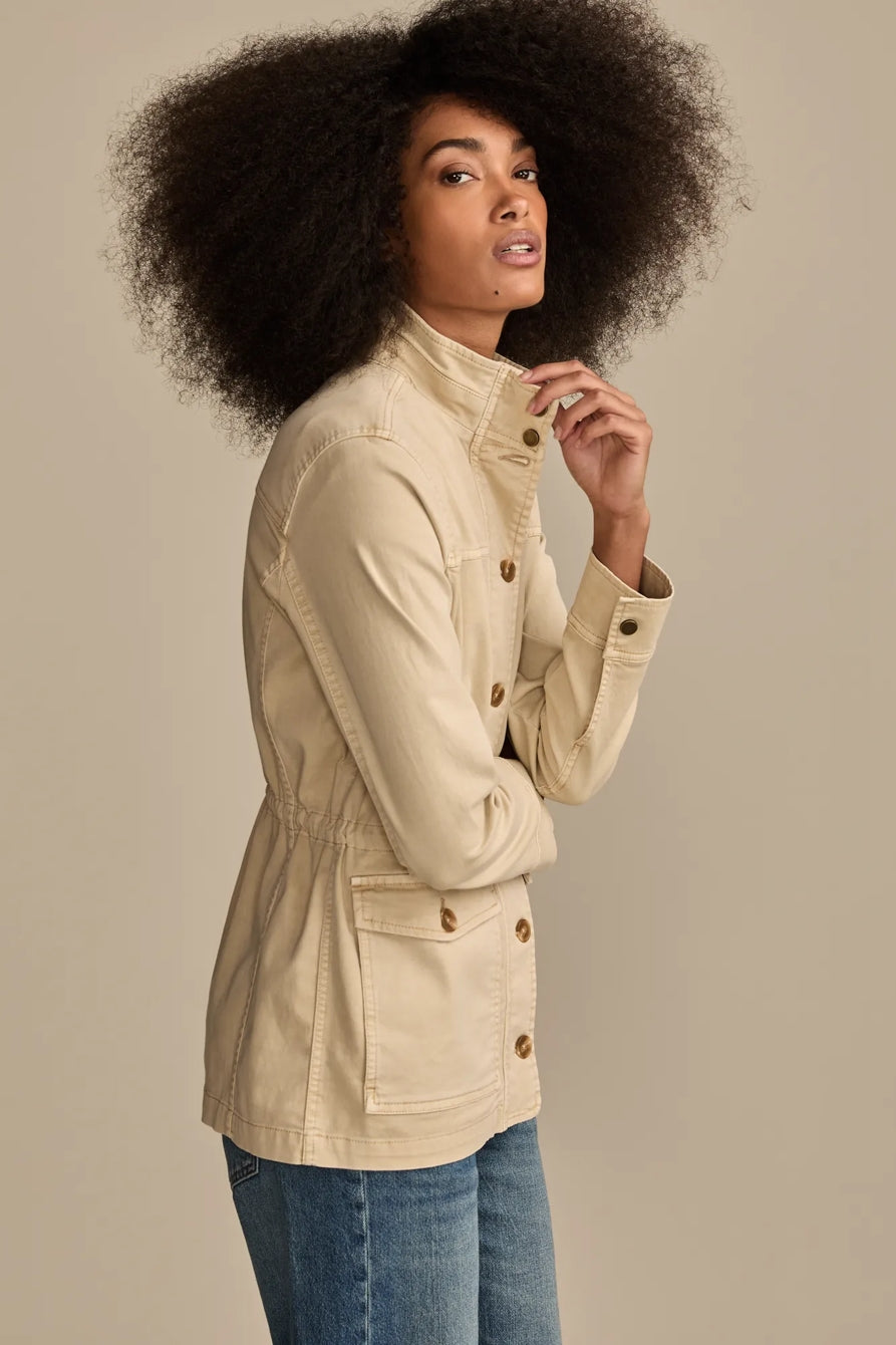 Woman wearing a tan Lucky Brand utility jacket with pockets and cinched waist, paired with blue jeans.