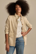 Woman wearing a light beige Lucky Brand utility jacket over a white t-shirt and blue jeans.