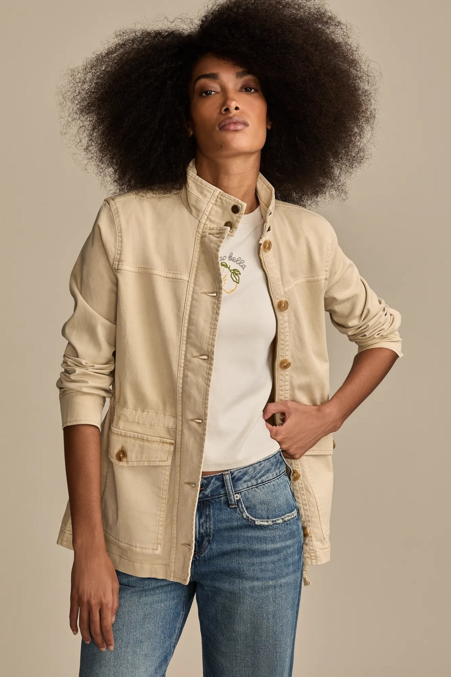 Woman wearing a light beige Lucky Brand utility jacket over a white t-shirt and blue jeans.