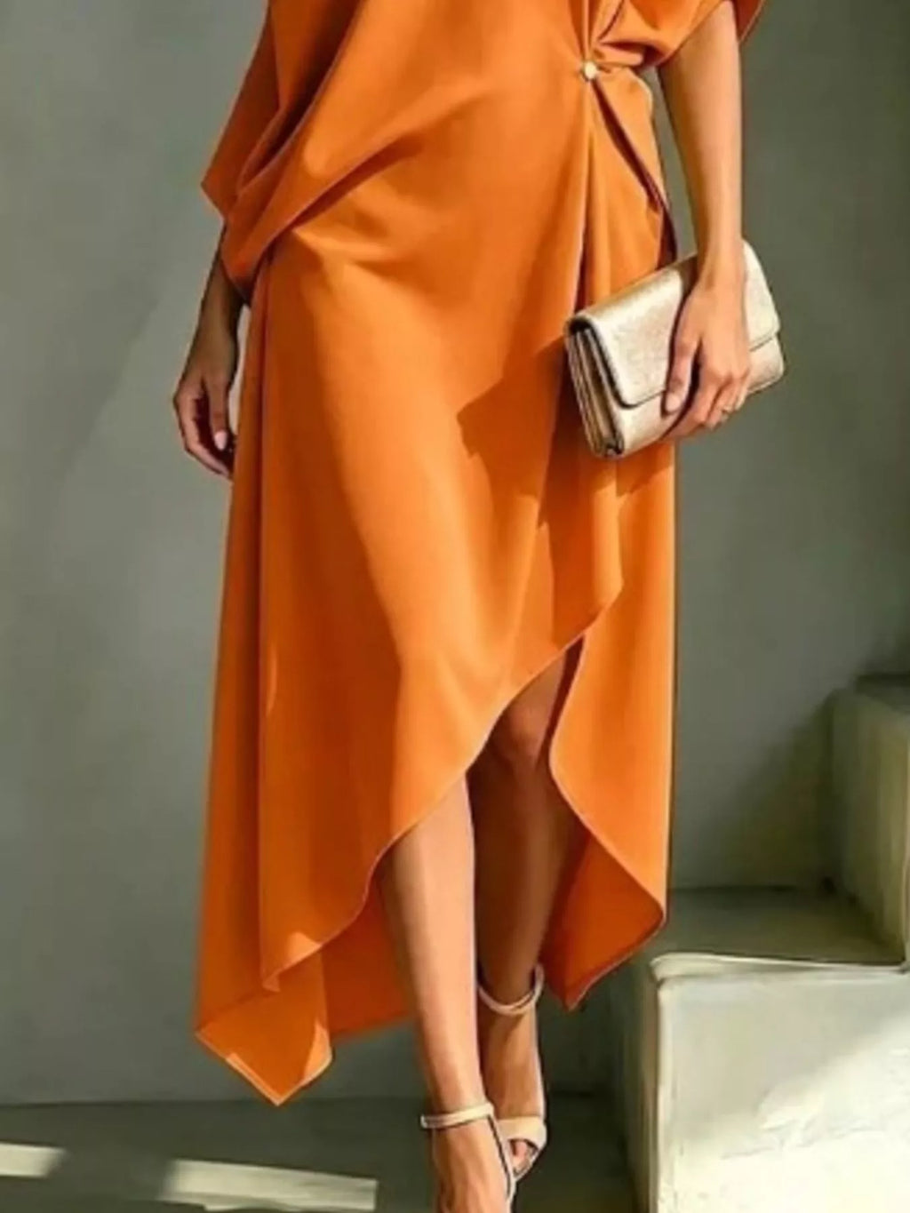 Plus size orange asymmetrical one-shoulder drape dress with a gold clutch.