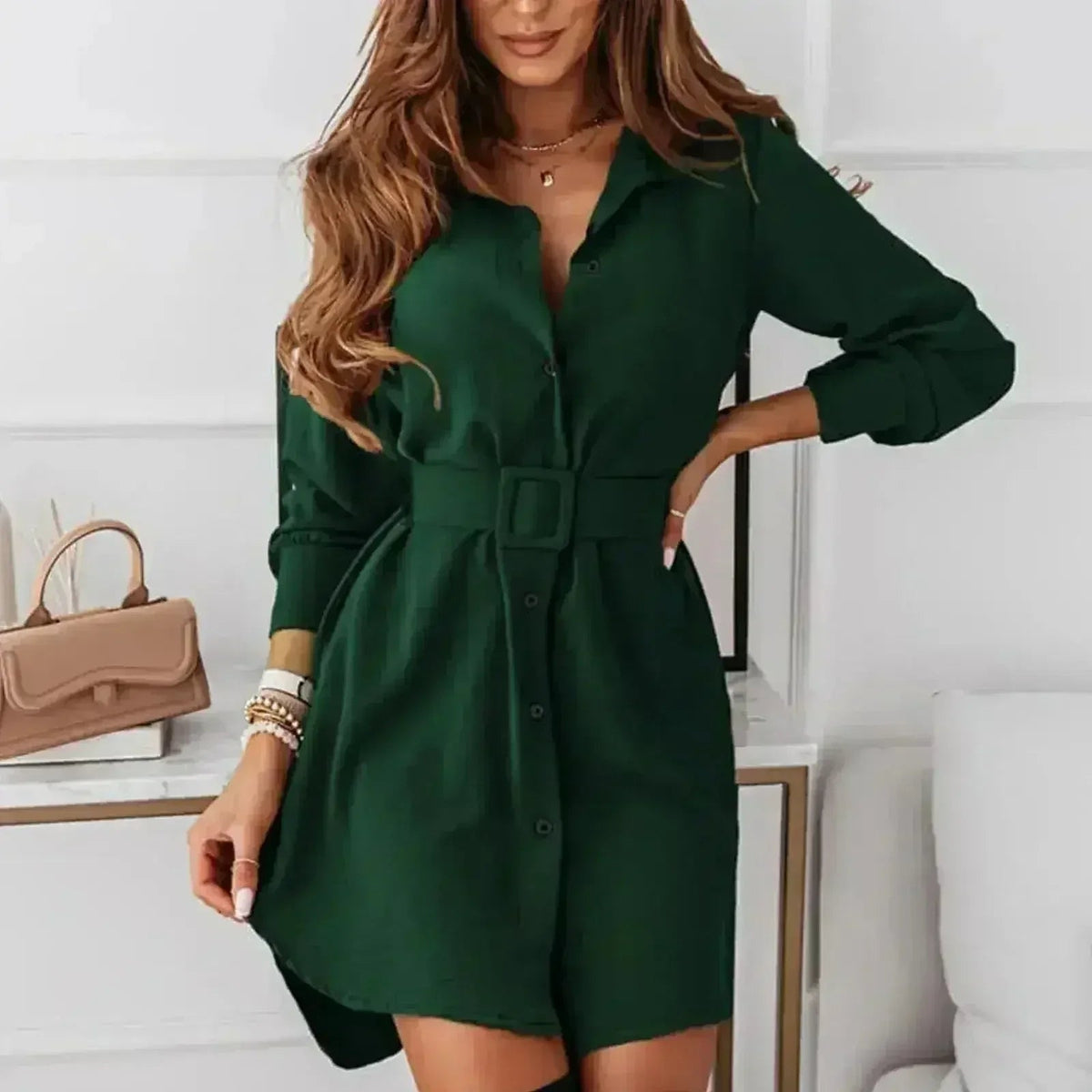 Woman wearing a green A-line shirt dress with a belt and long sleeves.