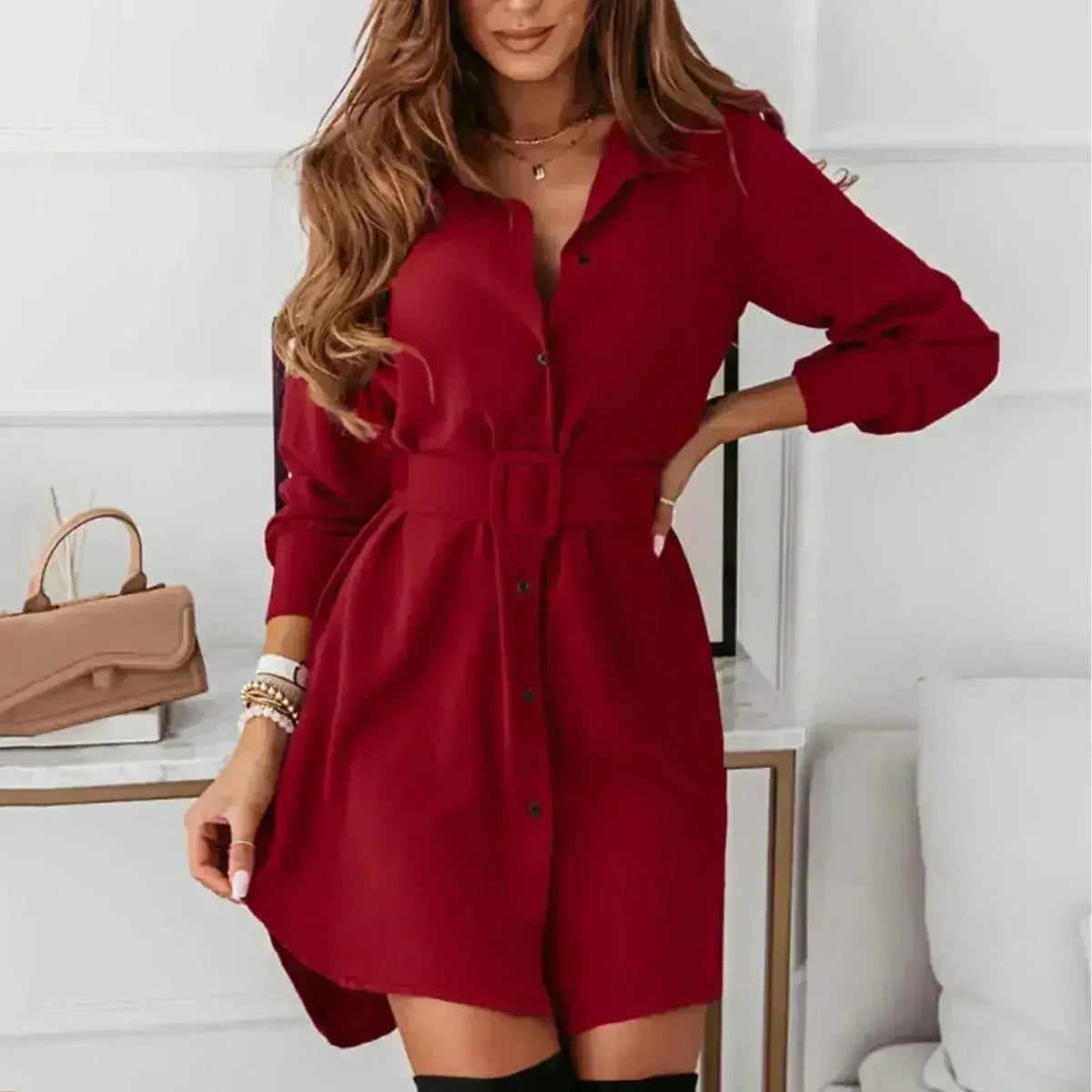 Woman wearing a red A-line shirt dress with a belt and long sleeves.