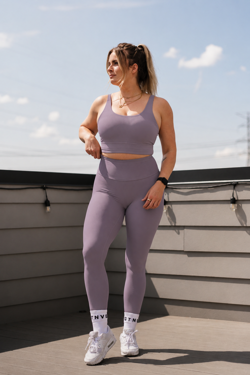 Woman wearing Alyth Active Devoted Lite High Rise Ribbed Leggings in lilac and a matching sports bra.
