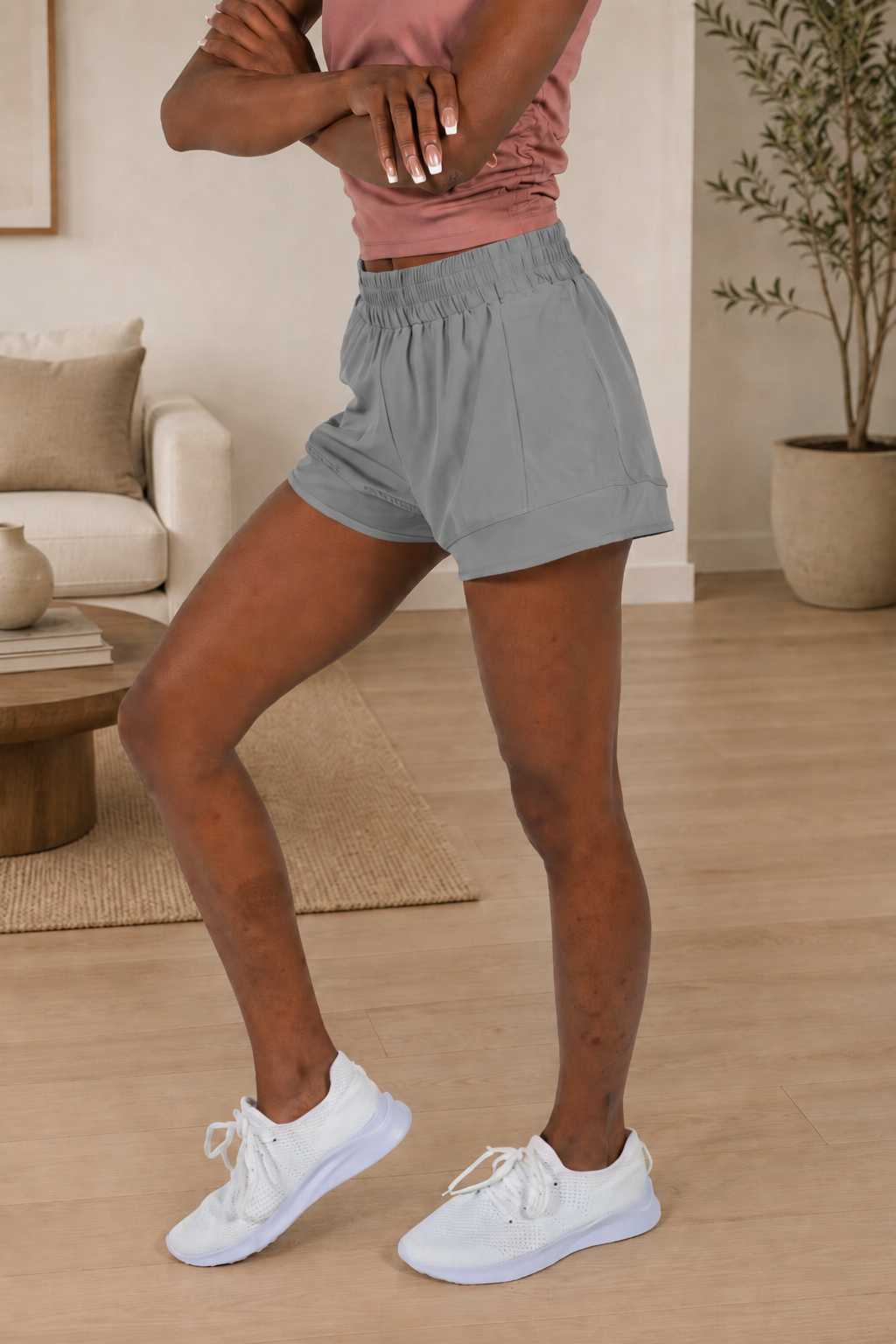 Woman wearing grey Alyth Active Empowered V3 Mid Rise Shorts with white sneakers.