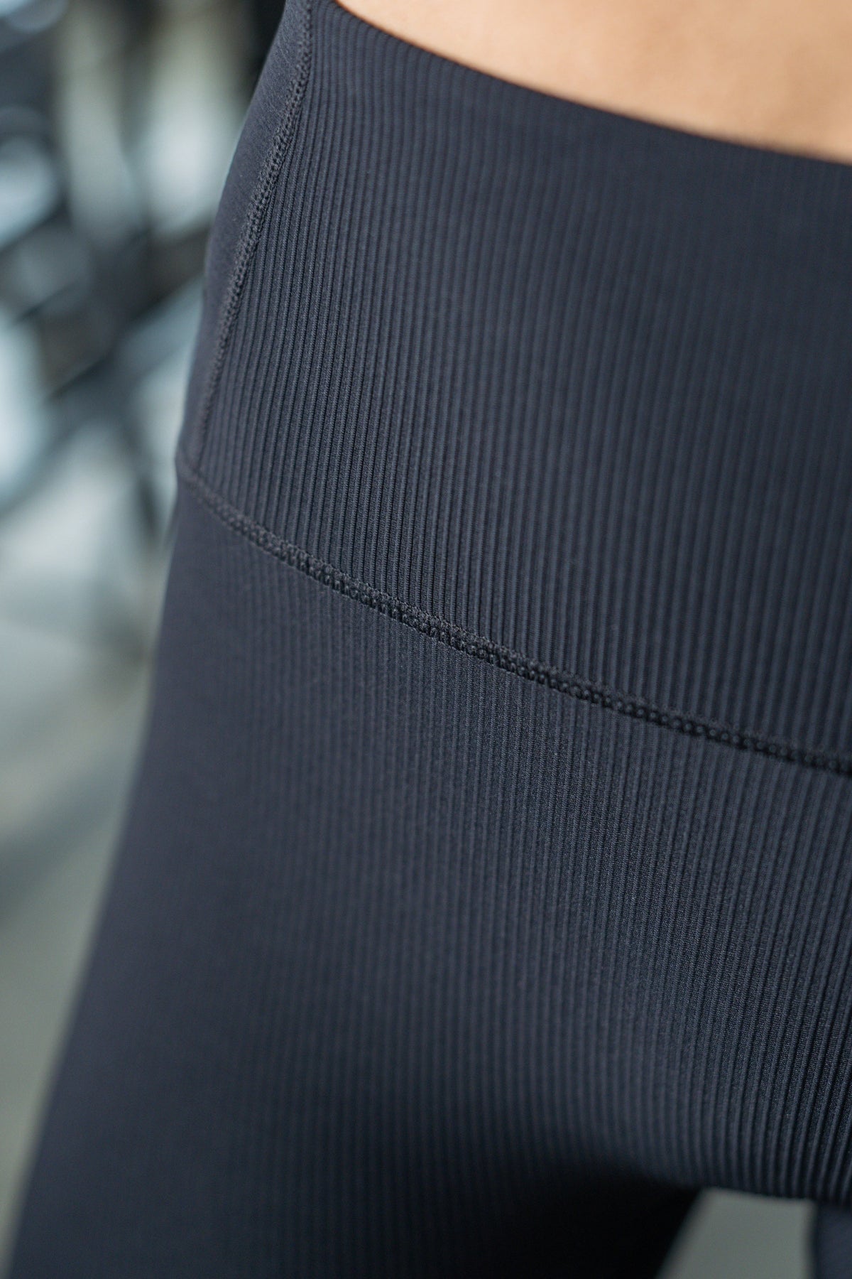 Close-up of black ribbed high-rise leggings with a visible seam.
