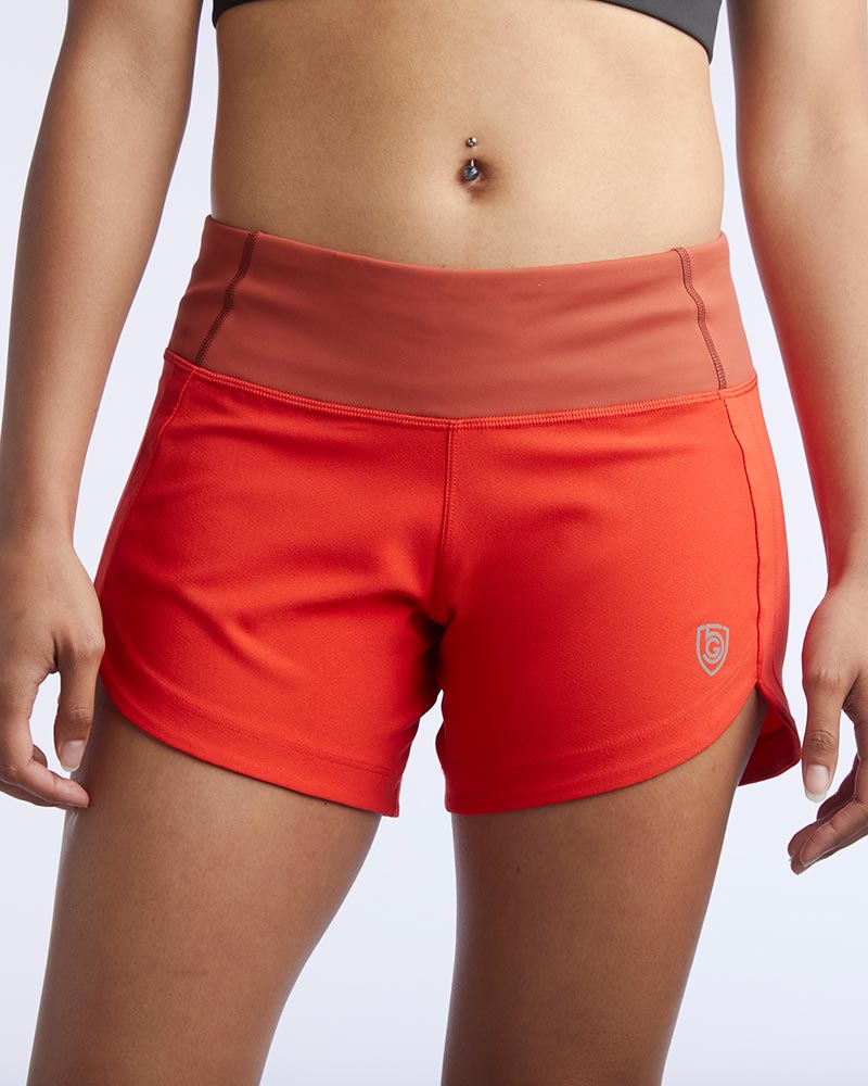 Goal Five Excel Women's red workout shorts with a rust-colored waistband and a subtle logo.