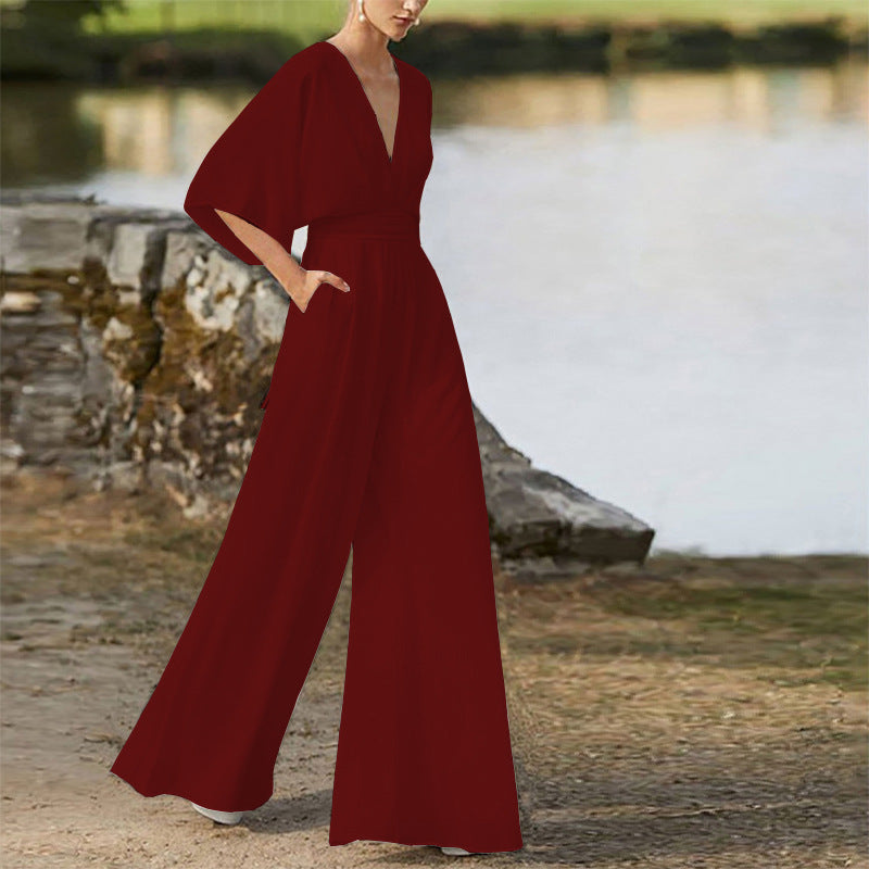 Woman wearing a deep V-neck, wide-leg, wine-red jumpsuit with short sleeves.