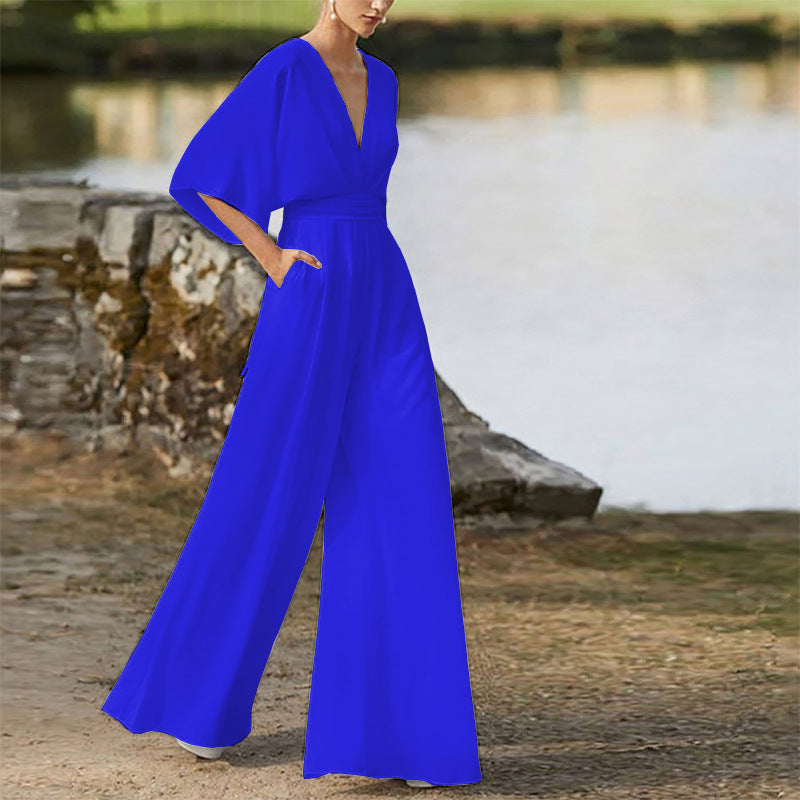 Woman wearing a royal blue wide-leg jumpsuit with a deep V-neck and short sleeves.