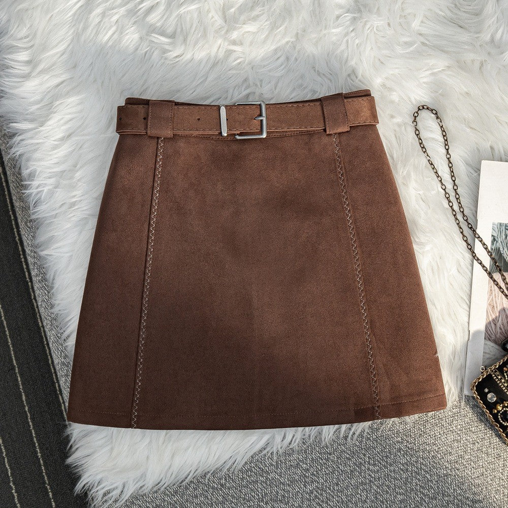 Brown suede A-line mini skirt with a high waist and matching belt on a white faux fur background.