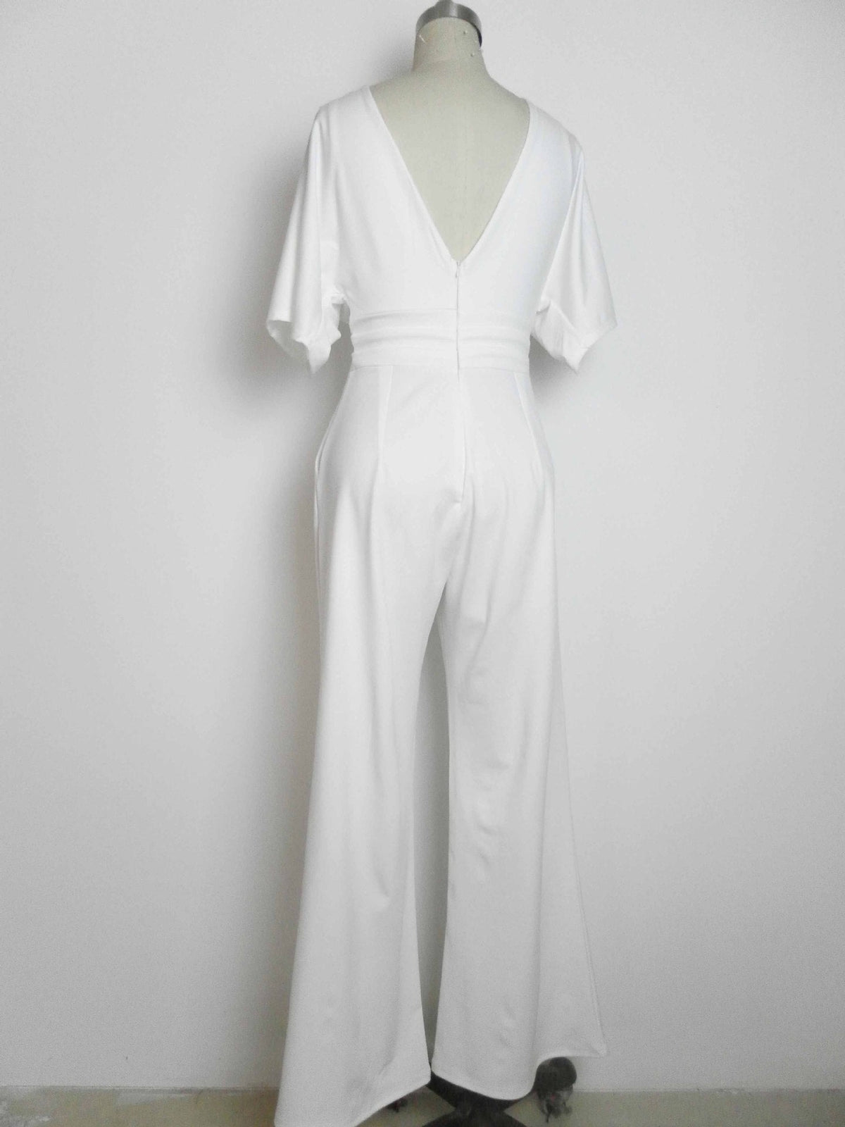 Back view of a white wide-leg jumpsuit with a deep V-neck and short sleeves, displayed on a mannequin.