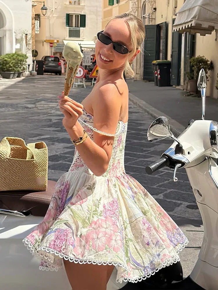 Woman in a floral A-line dress with spaghetti straps and lace trim, holding a gelato cone.