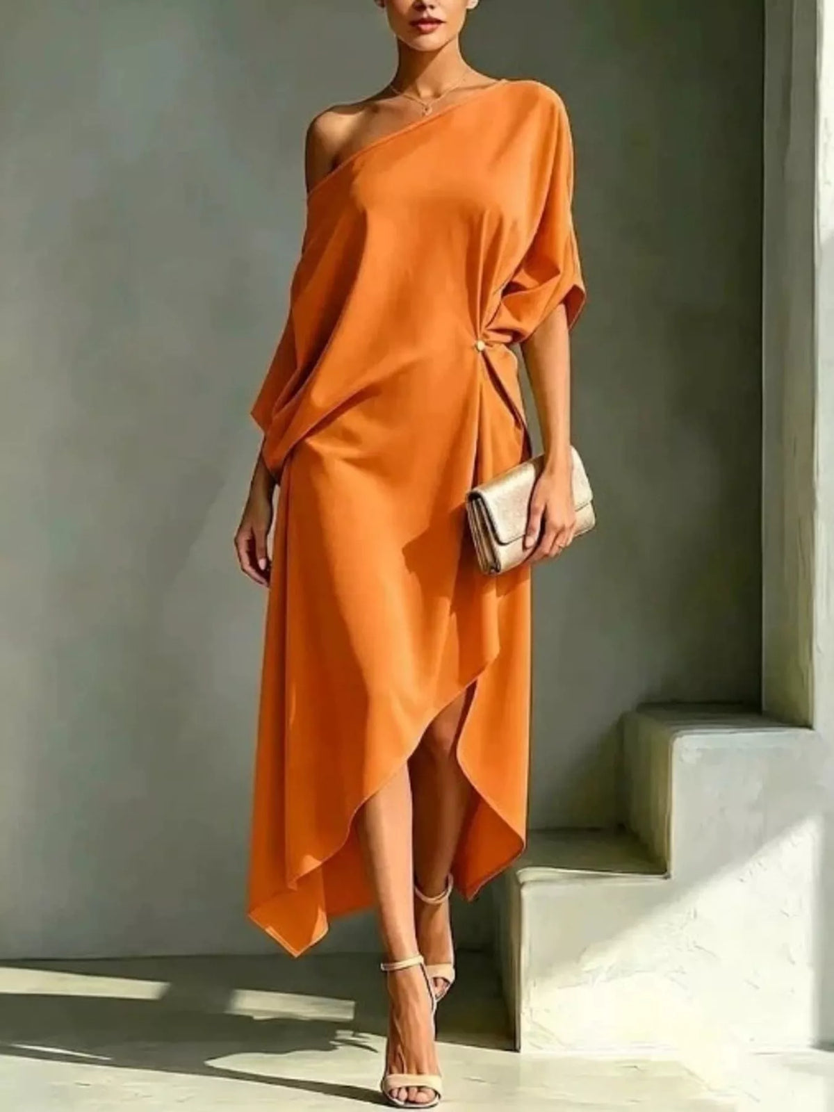 Plus size orange asymmetrical one-shoulder drape dress with a gold clutch and nude heels.