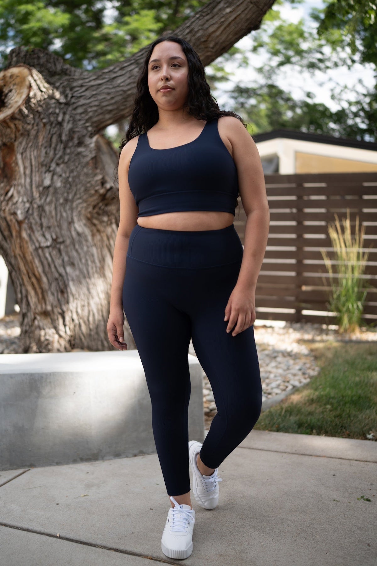 Woman wearing navy blue high-rise ribbed leggings and a matching sports bra.
