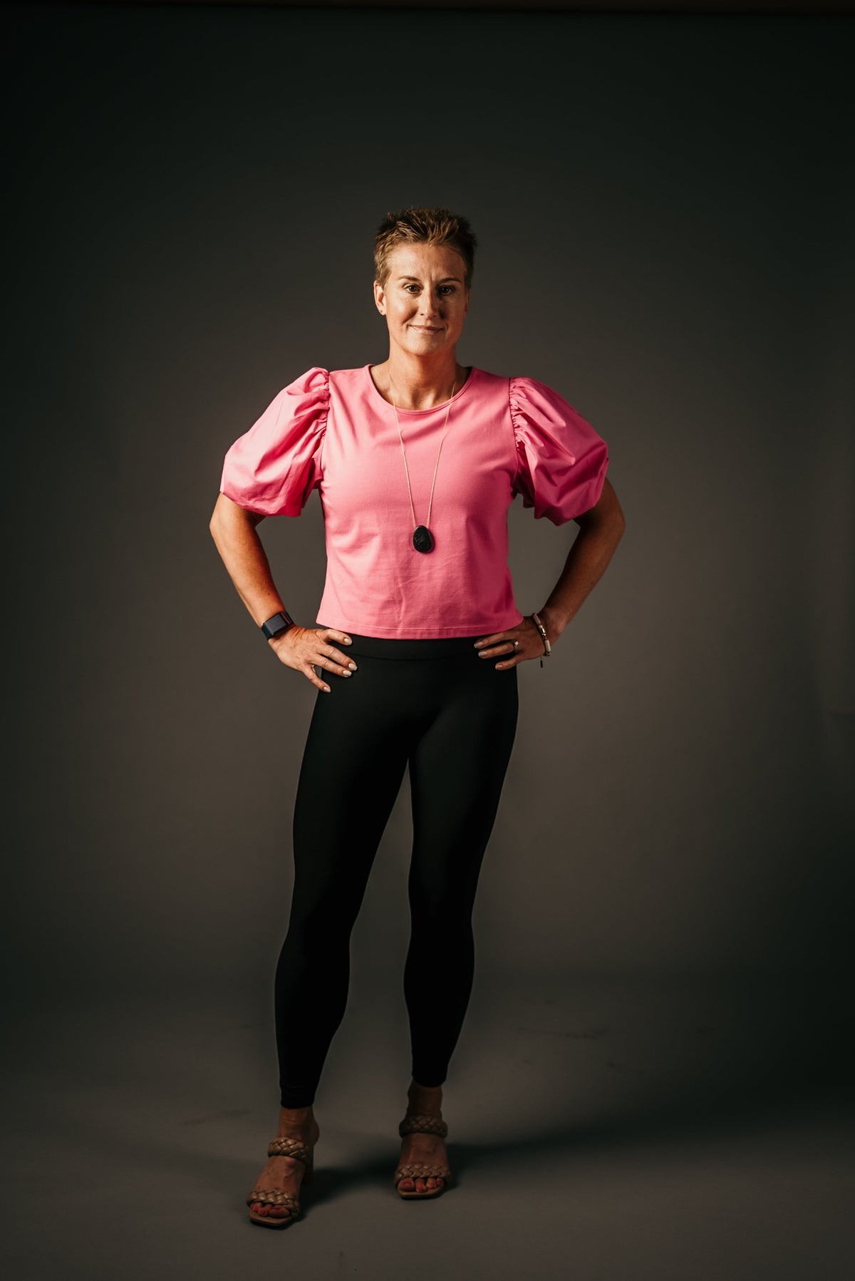 Woman wearing black Alyth Active Devoted Lite High Rise Ribbed Leggings and a pink puff-sleeve top.