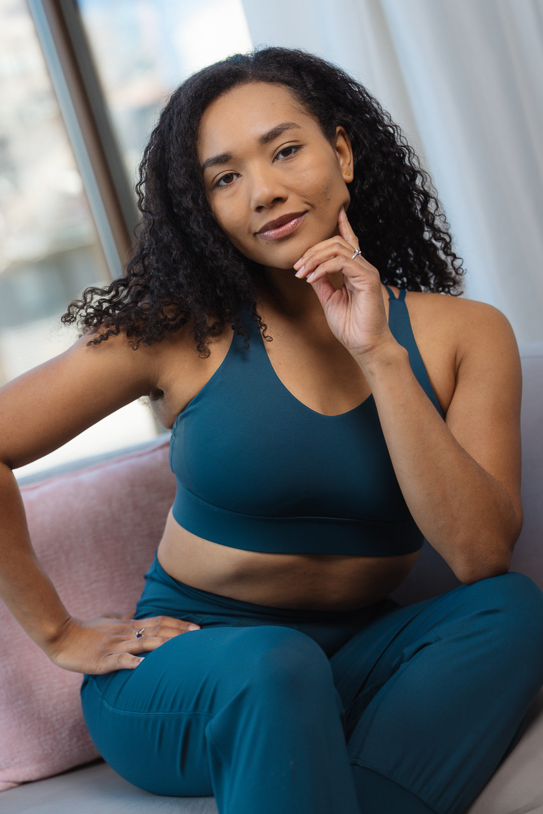 Woman wearing a teal GRAVITY adventurous V2 sports bra with a V-neckline and matching leggings.