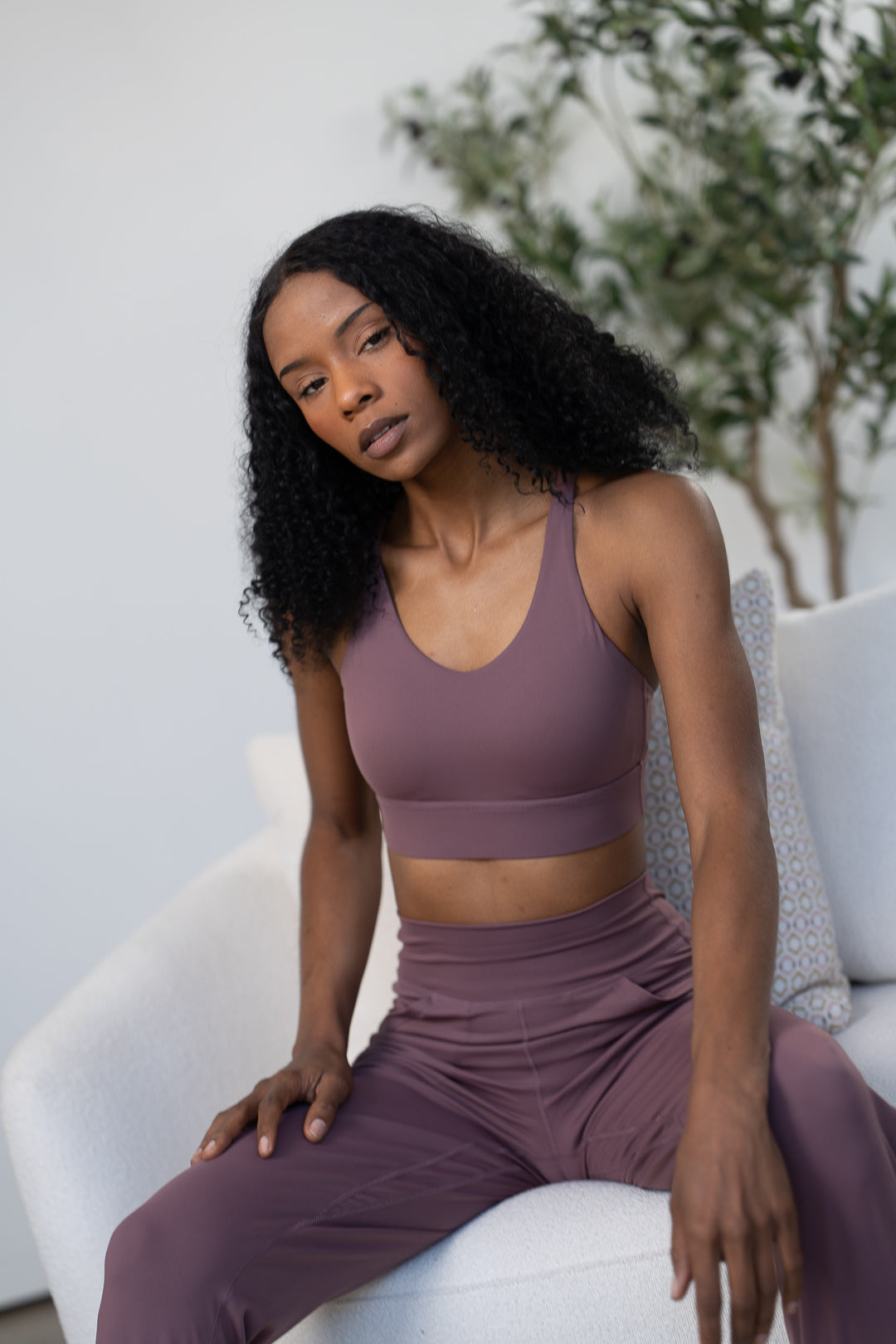 Woman wearing a dark mauve GRAVITY adventurous V2 sports bra and matching leggings.