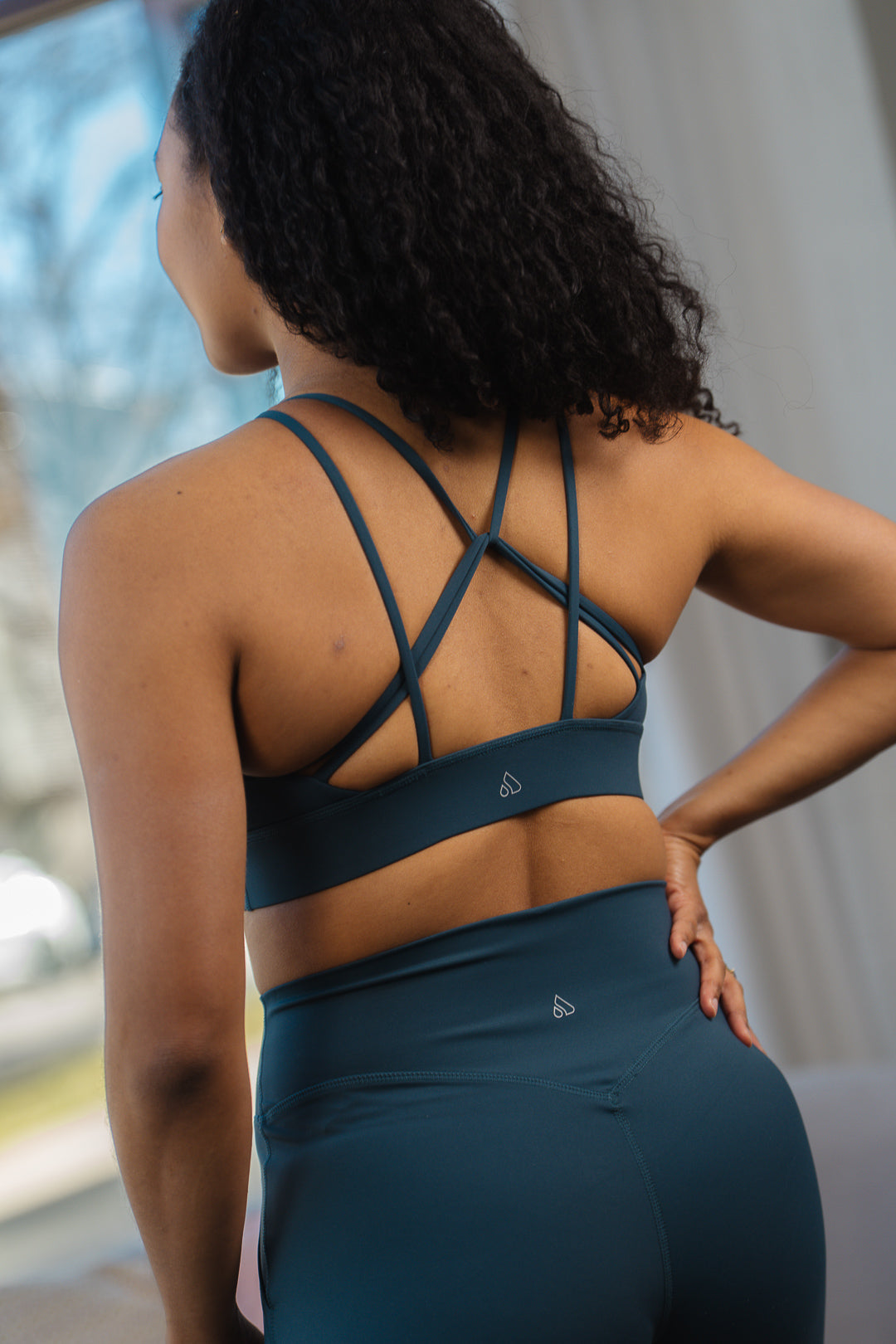 Back view of a woman wearing the GRAVITY adventurous V2 sports bra in ocean depth with strappy back.