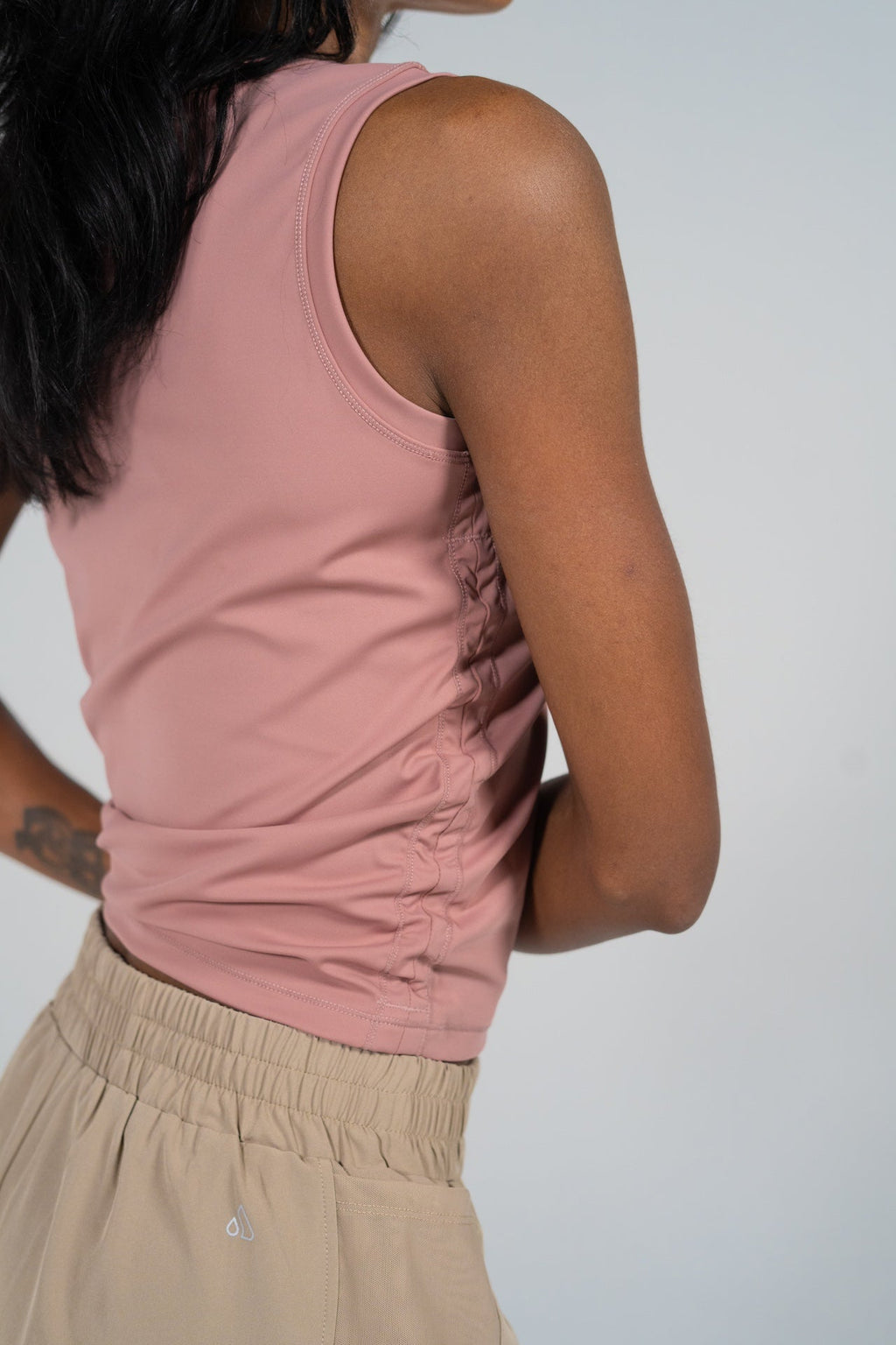 Back view of a woman wearing the GRAVITY soaring tank in damask pink with cinched side details.