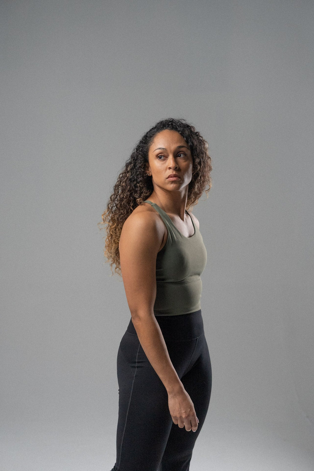 Woman wearing a cool mint Alyth Active Rebellious High Impact Crop Bra and black leggings, looking to the side.