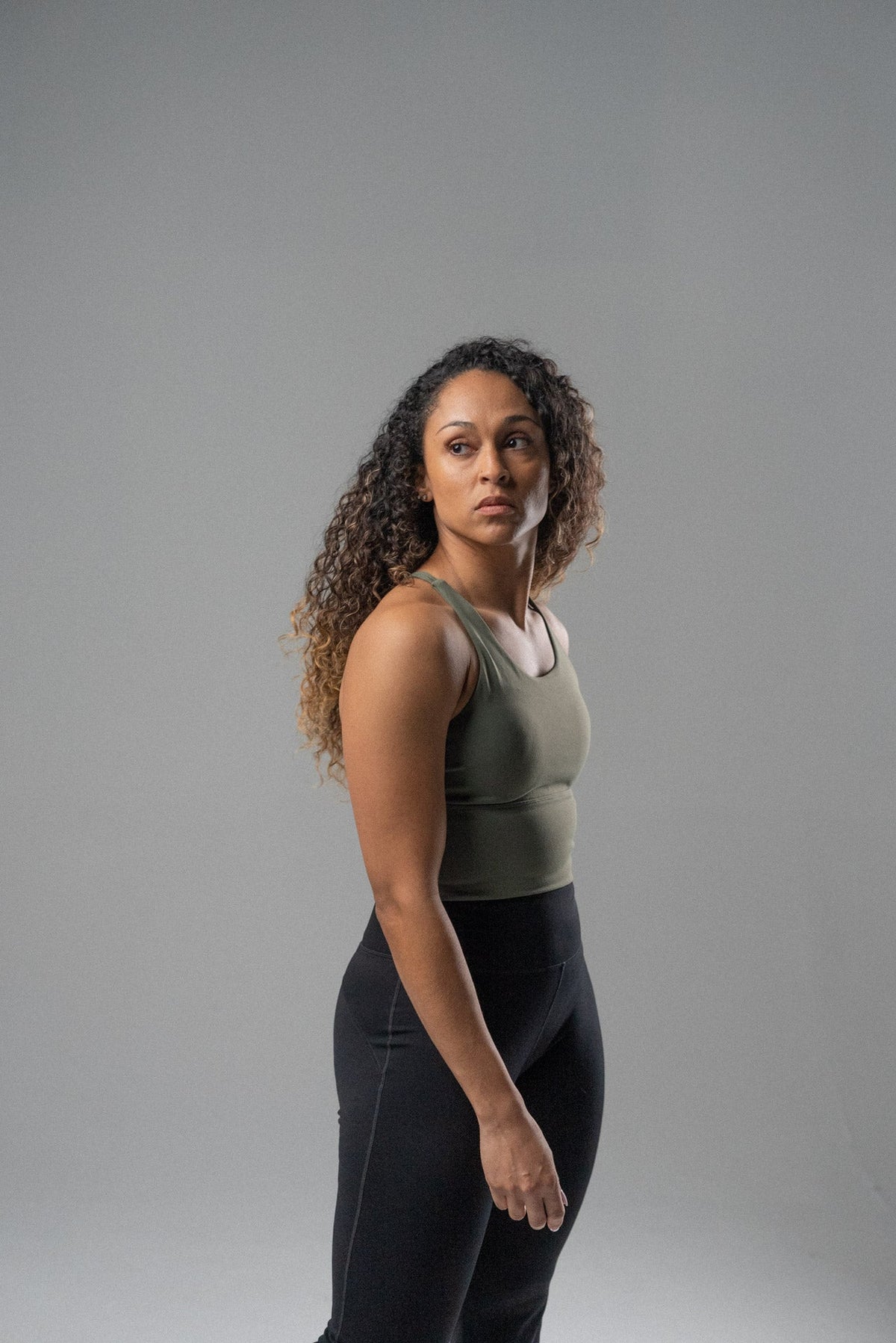 Woman wearing a cool mint Alyth Active Rebellious High Impact Crop Bra and black leggings, looking to the side.
