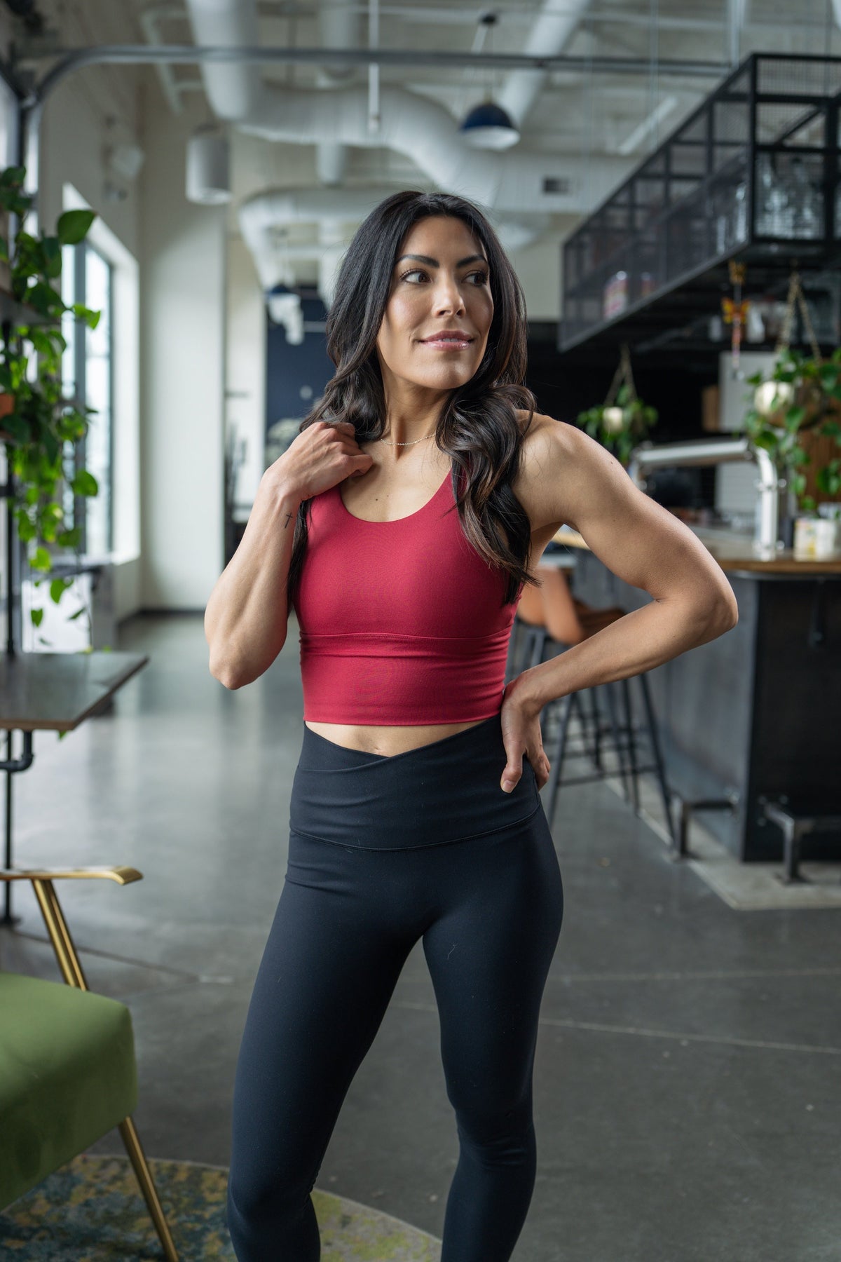 Woman wearing a deep red high-impact crop bra with black leggings, posing indoors.