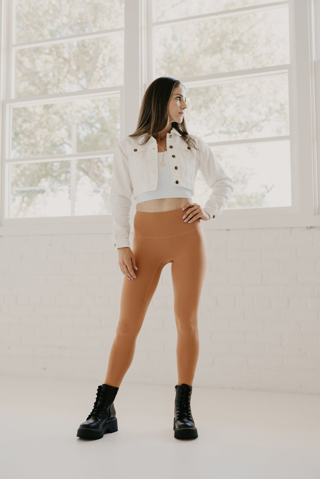 Woman wearing Alyth Active Rebellious High Impact Crop Bra in white with orange leggings and black boots.