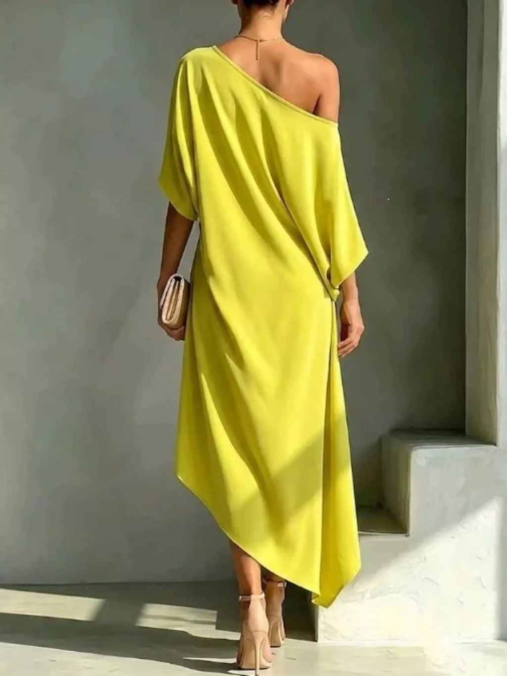 Plus size yellow asymmetrical one-shoulder drape dress with a clutch and heels.