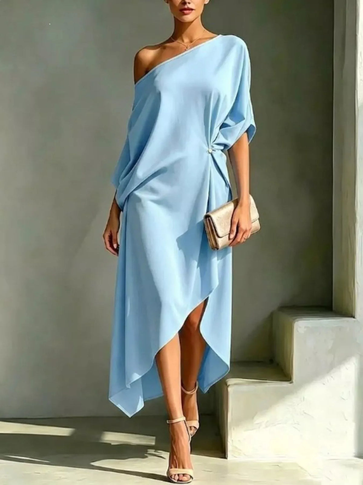 Plus size light blue asymmetrical one-shoulder drape dress with a gold clutch and nude heels.