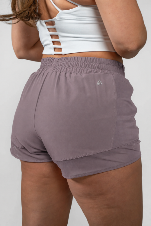 Alyth Active Empowered V3 Mid Rise Shorts in a muted purple color, shown from the back.
