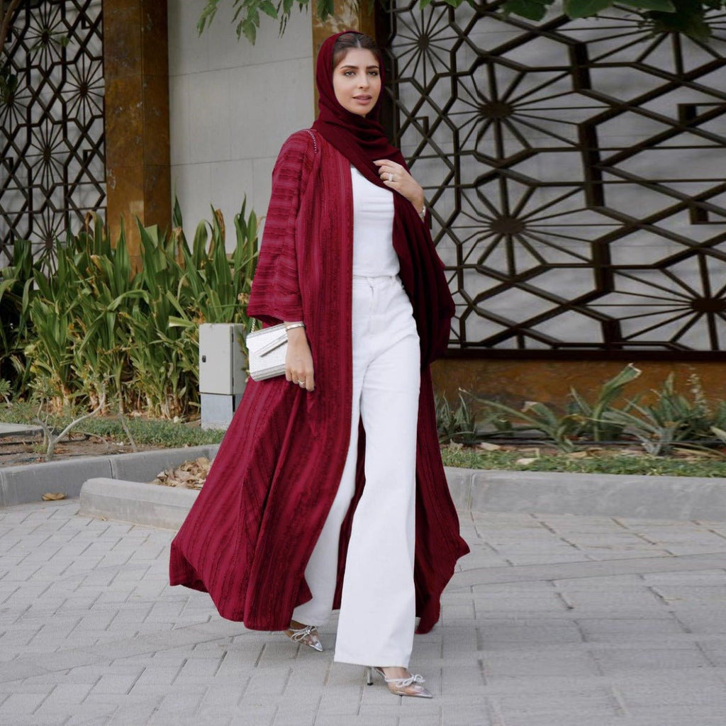 Woman wearing a maroon vintage knitted longline open front abaya over a white top and trousers.