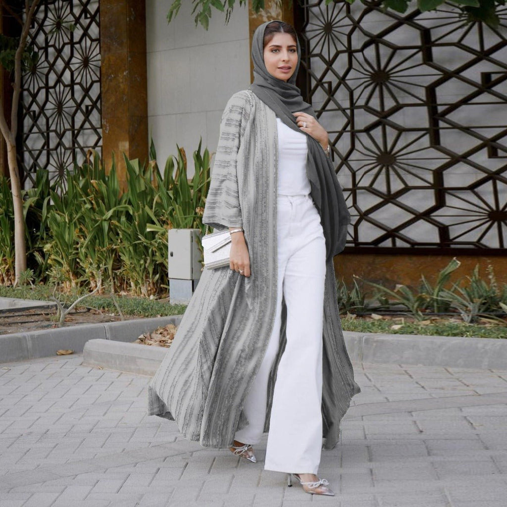 Woman wearing a grey vintage knitted longline open front cardigan abaya over white pants.