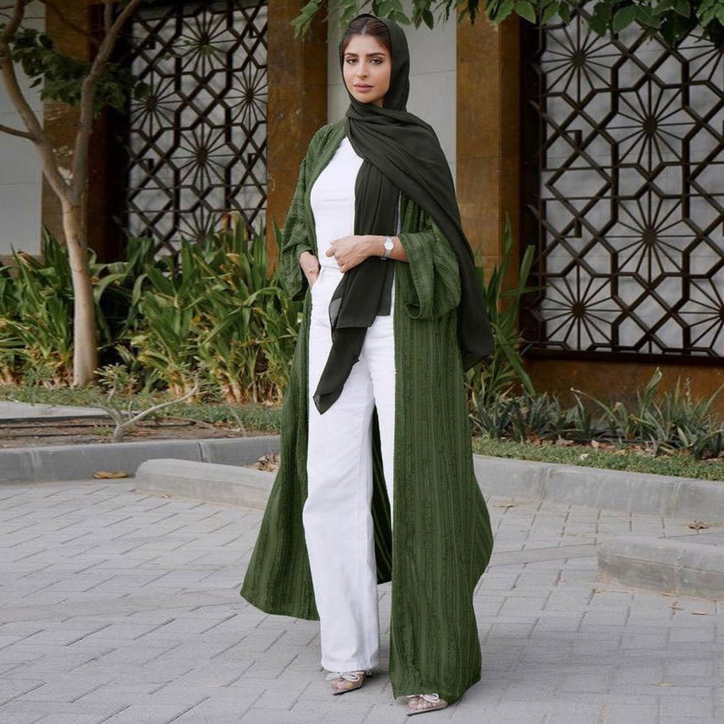 Woman wearing a dark green vintage knitted longline open front abaya over a white outfit.