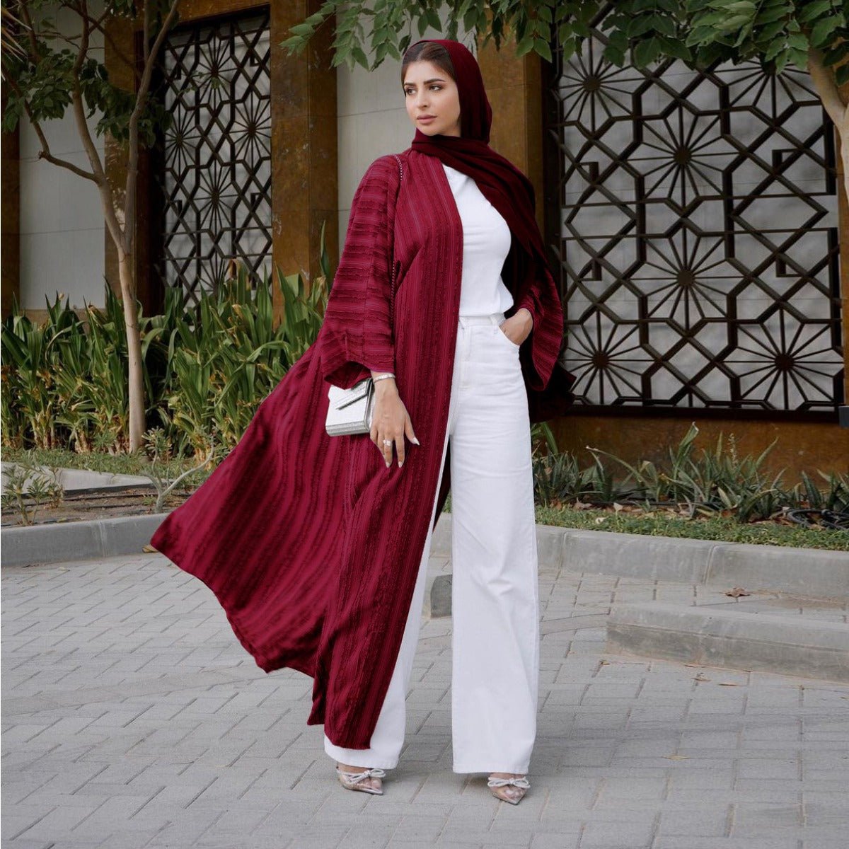Woman wearing a maroon vintage knitted longline open front abaya over a white top and pants.