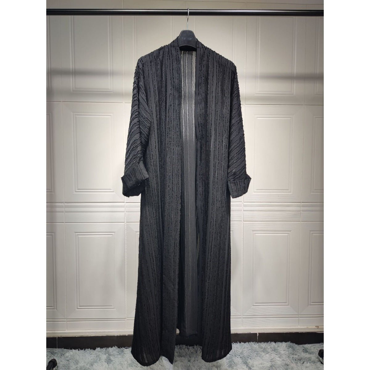 Black vintage knitted longline open front abaya with vertical textured stripes on a hanger.