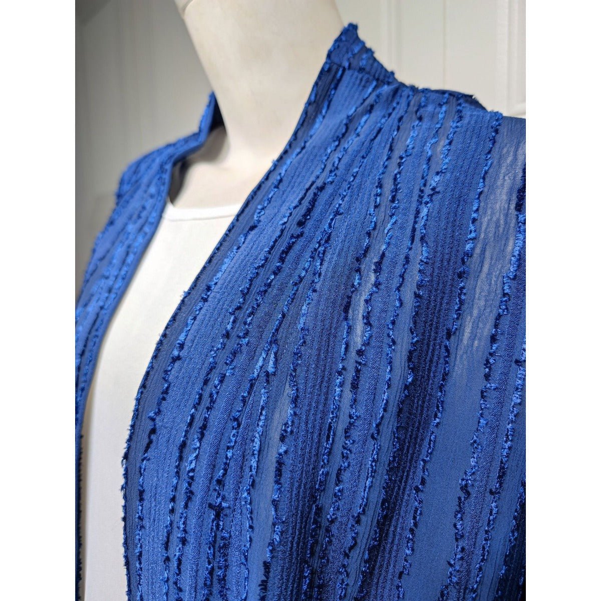 Close-up of a blue vintage knitted cardigan abaya with vertical stripes and fringe details.
