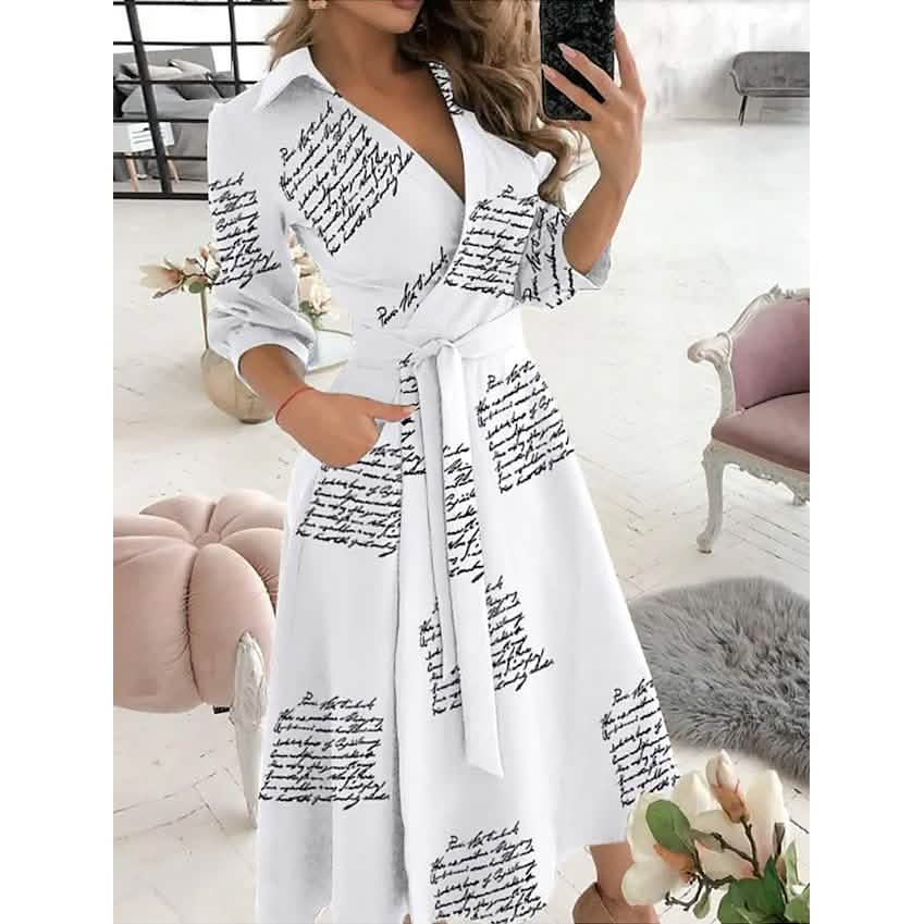 Woman wearing a white A-line midi dress with a black script print and a white tie belt.
